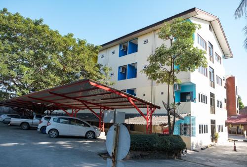 a parking lot with cars parked in front of a building at Nim Hotel in Chiang Mai