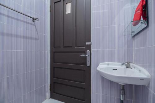 a bathroom with a black door and a sink at RedDoorz Syariah Plus @ Banjarbaru in Banjarmasin
