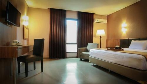 Habitación de hotel con cama, escritorio y silla en Raden Wijaya Hotel & Convention, en Mojokerto