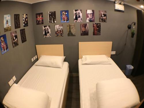 2 camas en una habitación con fotos en la pared en Soso Hostel en Hong Kong