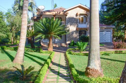 a house with palm trees in front of it at Mama Thea homes in Moshi