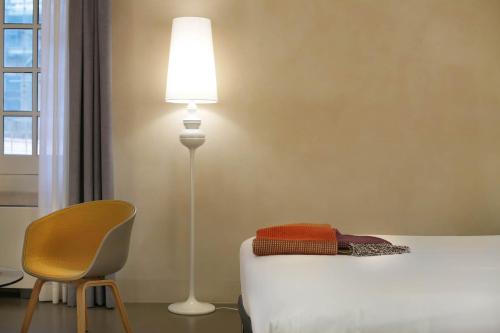 a bedroom with a bed and a lamp and a chair at Hotel Palazzo Grillo in Genova