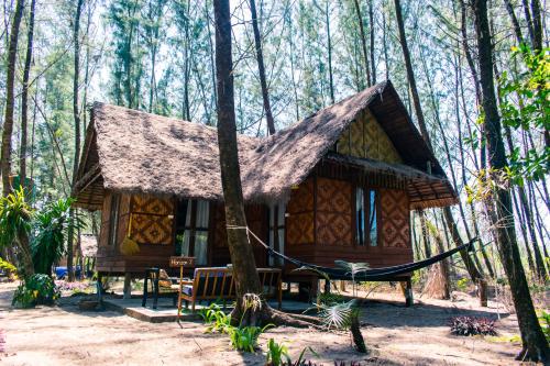 a cabin in the woods with a hammock in front at Horizon Eco Resort in Ko Phra Thong