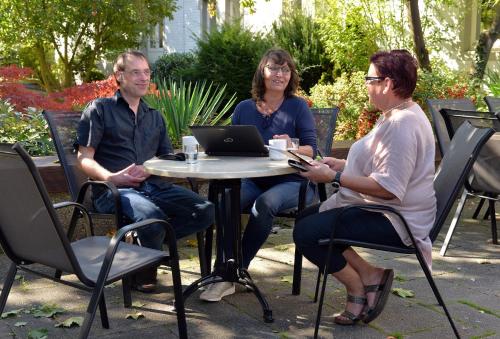 three people sitting at a table with a laptop at Nell-Breuning-Hotel in Herzogenrath