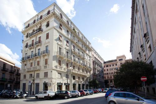 a white building with cars parked in front of it at Cosmopolitan Palermo in Palermo