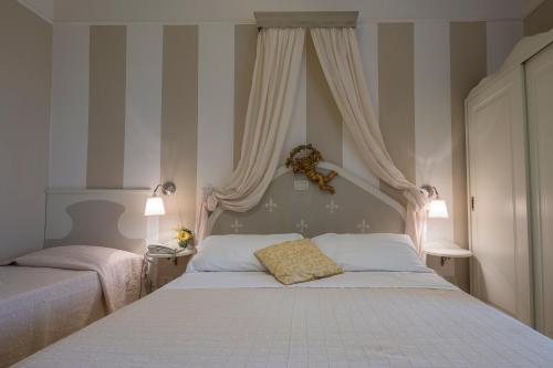a bedroom with two beds with curtains and a white bedspread at Hotel Mocambo piscina e spiaggia in San Benedetto del Tronto