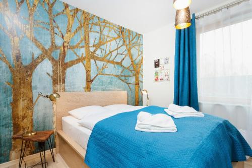 a bedroom with a blue bed with a tree mural at Apartments Kraków Masarska Free Parking by Renters in Krakow
