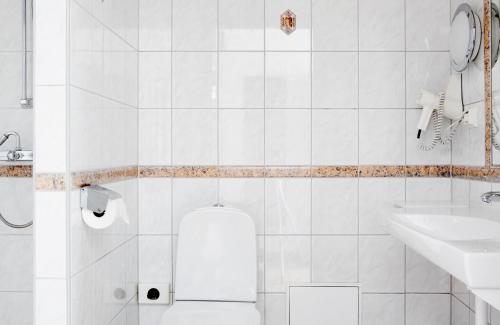 a white bathroom with a toilet and a sink at Comfort Hotel Eskilstuna in Eskilstuna