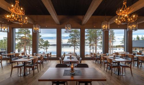 a restaurant with tables and chairs and large windows at Wilderness Hotel Inari & Igloos in Inari