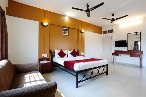 a bedroom with a bed and a couch in a room at HMR Hotels - Hotel HMR Royal Inn in Pune