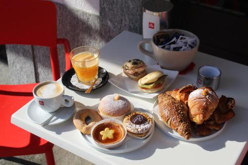 a table topped with plates of pastries and coffee and drinks at Camere Centro Storico in Canelli