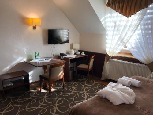a hotel room with a desk and a bed and a table at Hotel Dwór Choiny in Kazimierzówka