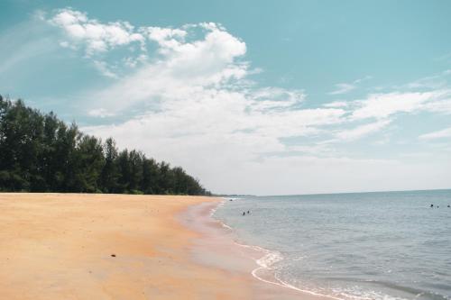 a beach with people in the water and trees at Horizon Eco Resort in Ko Phra Thong