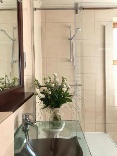 a bathroom with a glass sink with a vase of flowers at Villa Relax Vendégház in Gárdony
