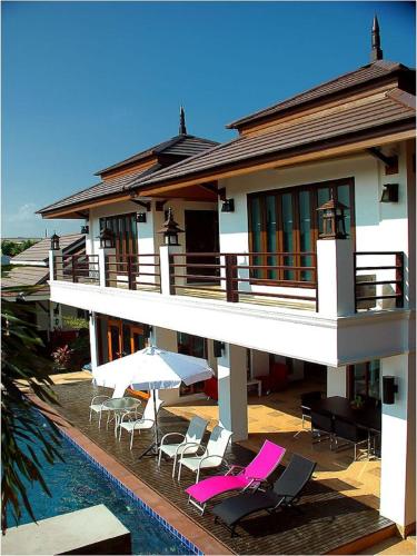 a house with chairs and umbrellas next to a swimming pool at Baan Soontree Resort in Chiang Rai