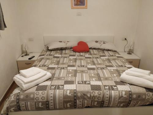 a bed with a red pillow sitting on top of it at Casa Di Girolamo in Predazzo