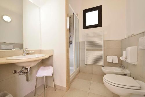 La salle de bains blanche est pourvue de toilettes et d'un lavabo. dans l'établissement Futura Club Baja Bianca, à San Teodoro
