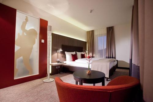een hotelkamer met een bed en een rode stoel bij bigBOX ALLGAEU Hotel in Kempten