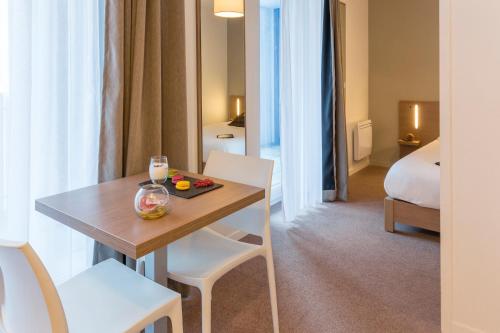 una camera da letto con tavolo e sedie di Appart'City Confort Saint-Nazaire Océan a Saint-Nazaire