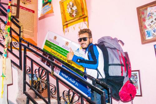 a man sitting in a backpack giving a thumbs up at Ouarzazate Youth Hostel YHO in Ouarzazate