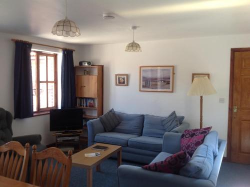 a living room with a blue couch and a tv at Stable Cottages in Cowes