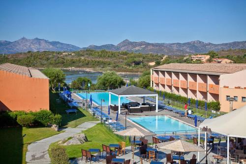 a resort with a pool and tables and chairs at Hotel Baja Bianca in San Teodoro