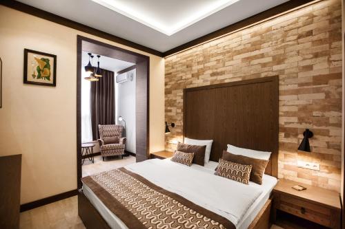 1 dormitorio con 1 cama grande y pared de ladrillo en SIMPLE HOTEL en Sochi