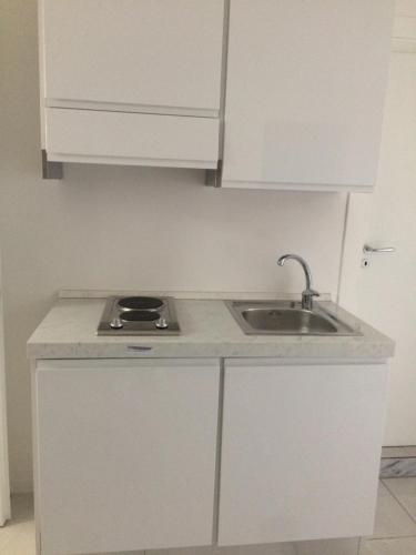 a kitchen with white cabinets and a sink at Live Naples in Naples