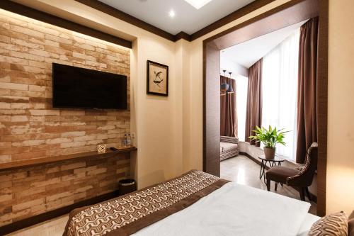1 dormitorio con pared de ladrillo y TV. en SIMPLE HOTEL en Sochi