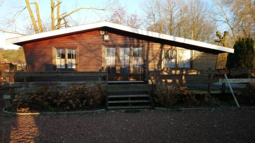 a small wooden house with a staircase in front of it at Chalet de vacances in Guisy