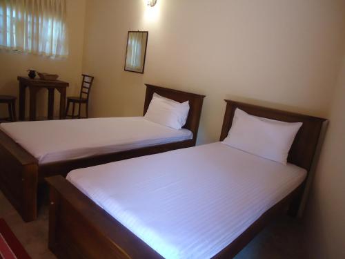two beds in a small room with two chairs at New Sanmi Resort in Malabe