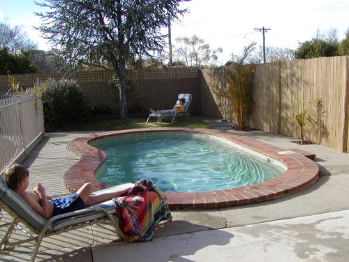 two people laying on chairs next to a small pool at Country Home Motor Inn in Shepparton