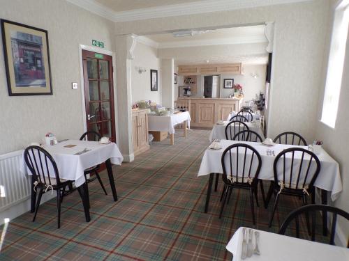 a restaurant with white tables and chairs and a kitchen at Stoneleigh Hotel in Skegness