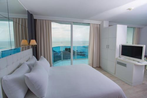 a bedroom with a white bed and a television at Le Bleu Hotel & Resort Kusadasi in Kusadası