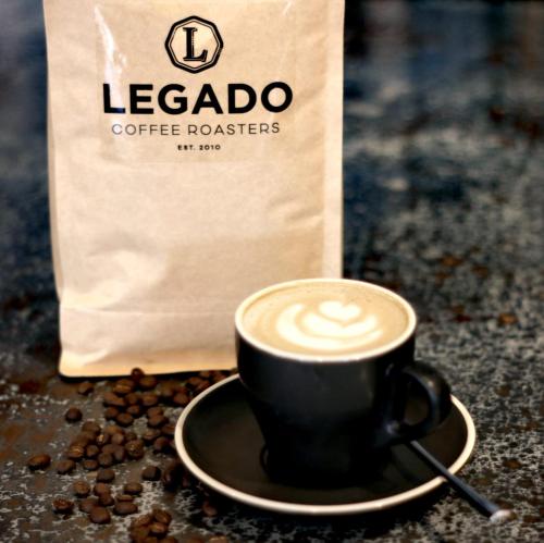 a cup of coffee on a plate next to a bag of coffee beans at The Junction Boutique Hotel in Plettenberg Bay