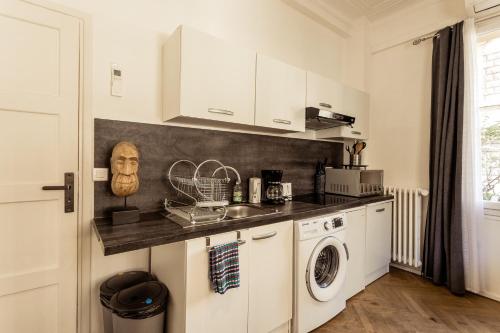 biała kuchnia z pralką i suszarką w obiekcie Apartment proche mer w Nicei