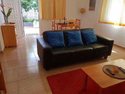 a living room with a black couch and a table at Casa Angel y Carmen (La Dama, La Gomera) in El Cercado