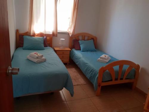 1 dormitorio con 2 camas, silla y ventana en Casa Angel y Carmen (La Dama, La Gomera), en El Cercado