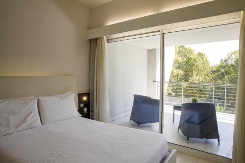1 dormitorio con 1 cama y 2 sillas y balcón en Lungotevere Suite, en Roma