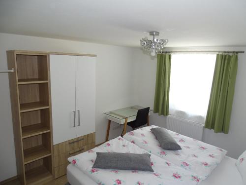 a bedroom with a bed and a desk and a window at Ferienwohnung Stegmühle in Faistenau