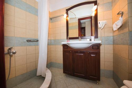 een badkamer met een wastafel, een spiegel en een douche bij Anemoessa Traditional Guesthouse in Miléai