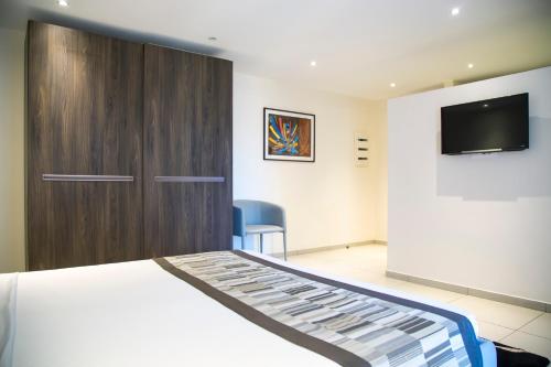 a bedroom with a bed and a tv on a wall at Le Ndiambour Hôtel et Résidence in Dakar