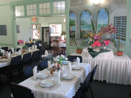 a dining room with tables with white tablecloths and flowers at Concord Christian Guesthouse in Durban