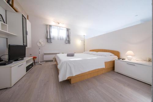 sypialnia z łóżkiem i telewizorem z płaskim ekranem w obiekcie Strma Apartments w mieście Vis