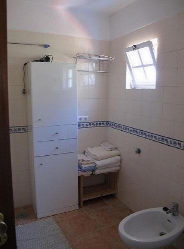 a small bathroom with a toilet and a window at Casa do avô Teixeira in Sesimbra