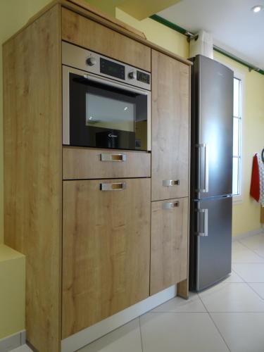 une grande armoire en bois avec un micro-ondes et un réfrigérateur dans l'établissement Appartement vue mer, Presqu'il de Giens, à Hyères