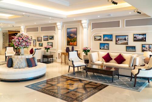 a lobby with couches and chairs and paintings at Al Ain Palace Hotel Abu Dhabi in Abu Dhabi