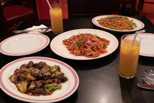 three plates of food on a table with two glasses of orange juice at Al Ain Palace Hotel Abu Dhabi in Abu Dhabi