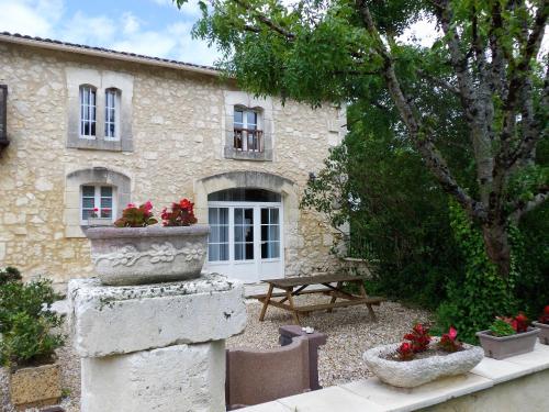 a stone house with a table and a bench in front of it at Domaine de Beaufort in Saint-Front-de-Pradoux