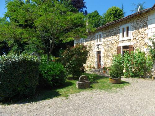 a stone house with trees and bushes in front of it at Domaine de Beaufort in Saint-Front-de-Pradoux